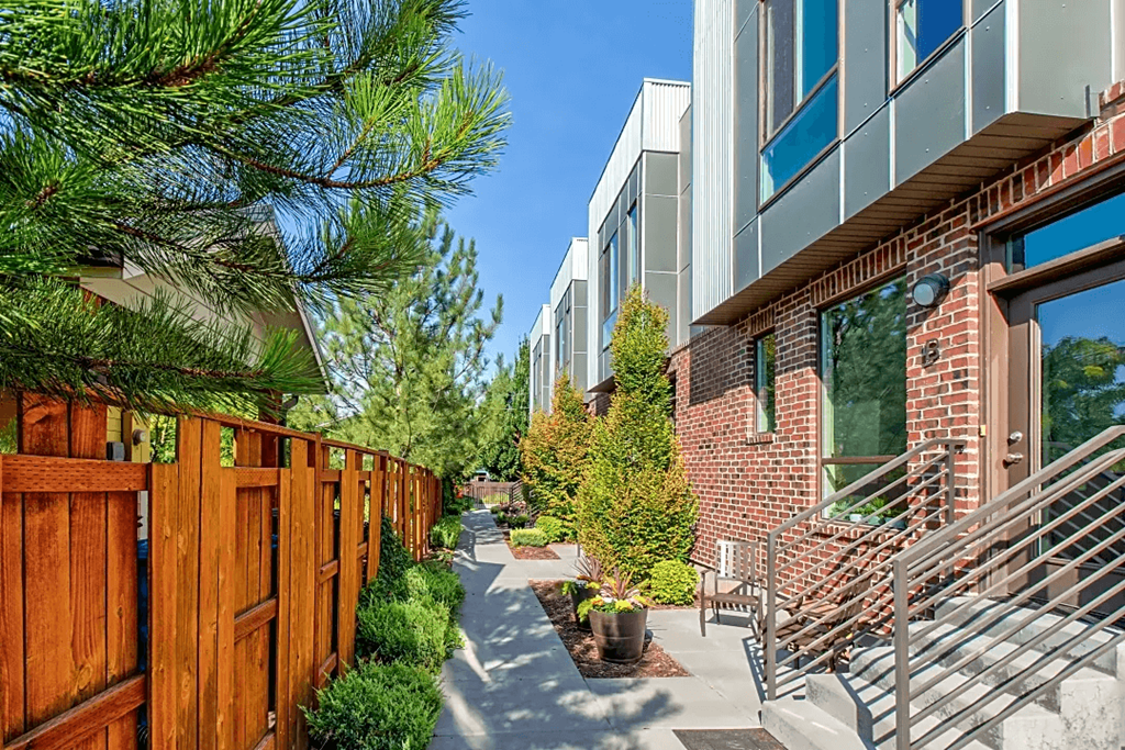 a patio with chairs and a wooden fence next to a brick building  at BlueKoi Townhomes for rent in Salt Lake City, UT