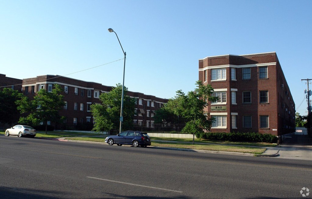 A street view of a residential area with cars parked on the side of the road.
