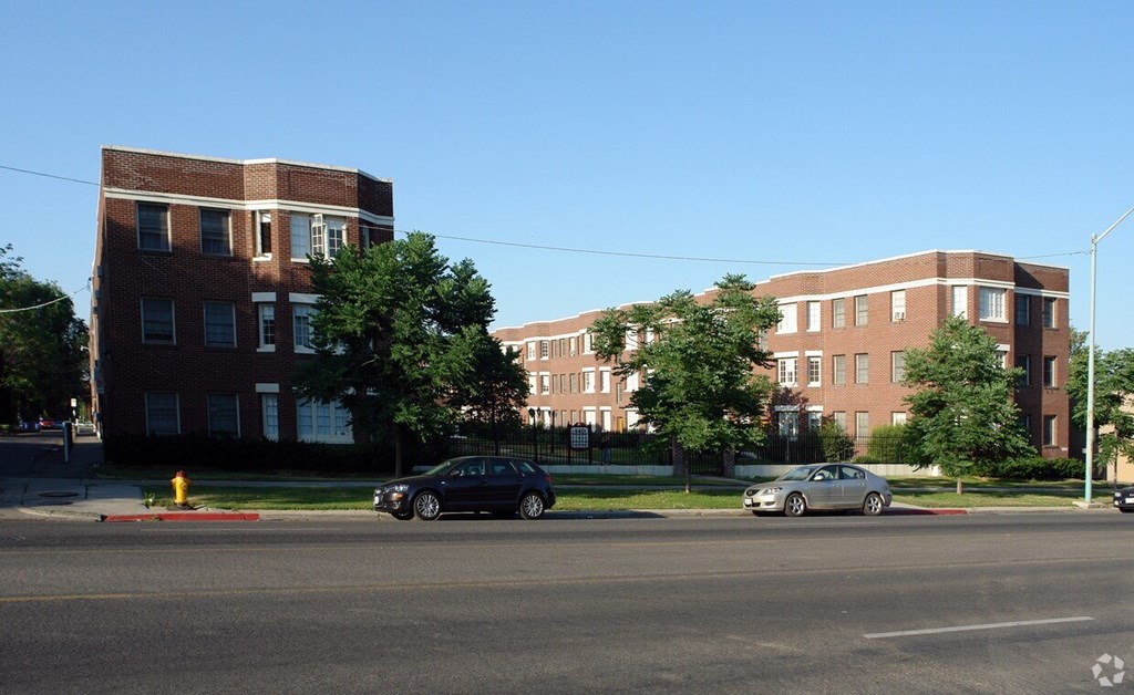 A black car is driving down a street past a red fire hydrant.
