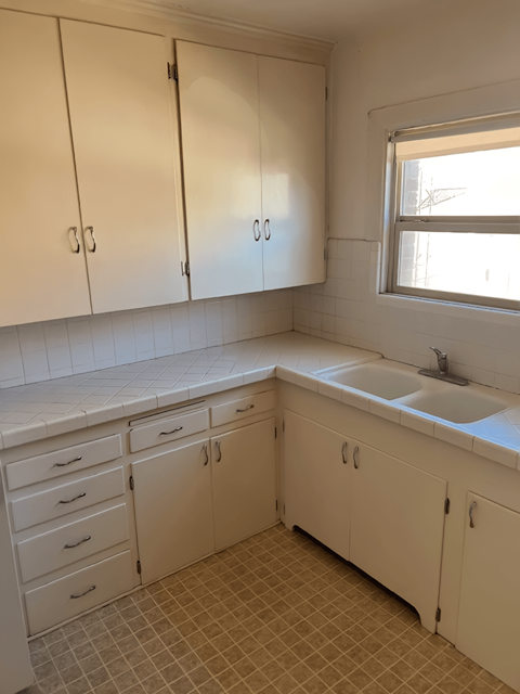 A kitchen with white cabinets and a tiled floor.