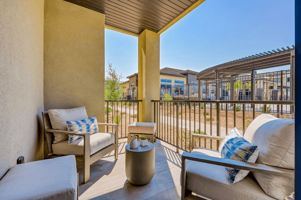 a balcony with a couch and chairs and a view of a building