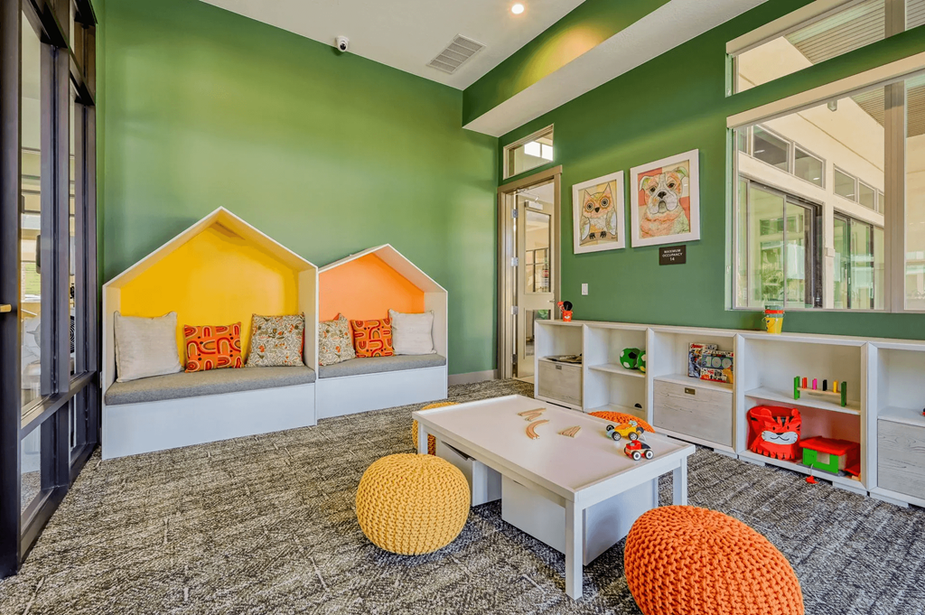 a play room with green walls and a table and chairs