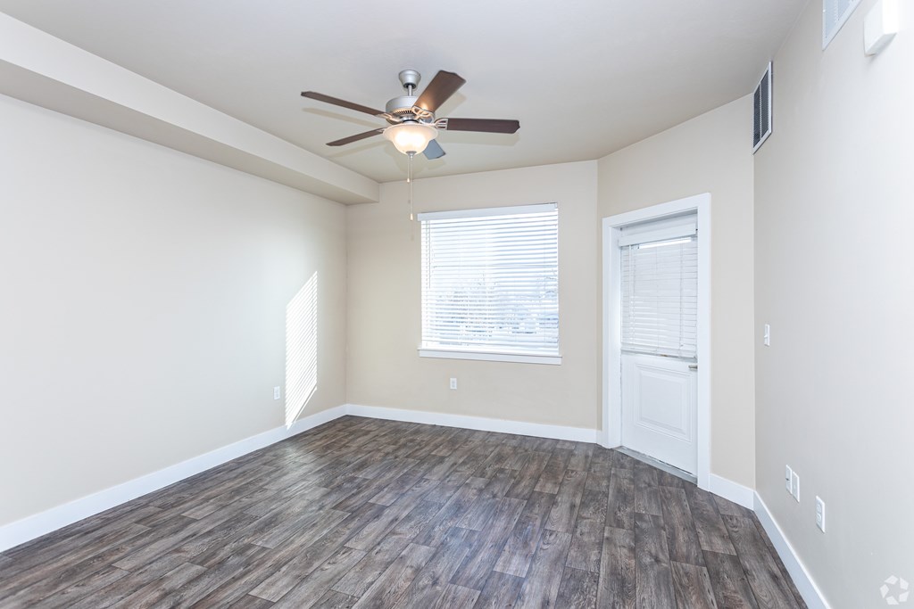 A room with a ceiling fan and wooden flooring.