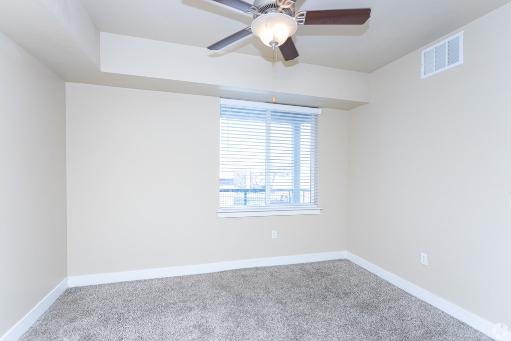 A room with a ceiling fan and a window with blinds.