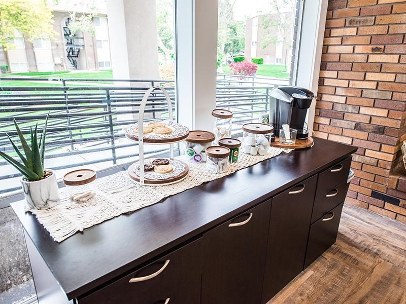 A coffee bar with a potted plant and a coffee maker on it.