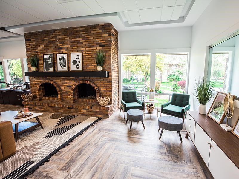 A living room with a brick fireplace and a green chair.