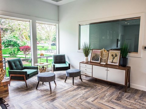 A living room with a green chair and a grey ottoman.
