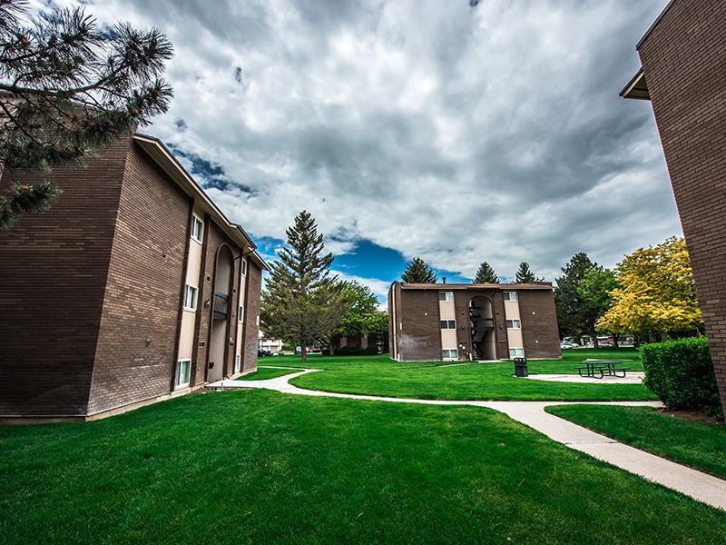 A grassy area with a pathway and two buildings on either side.