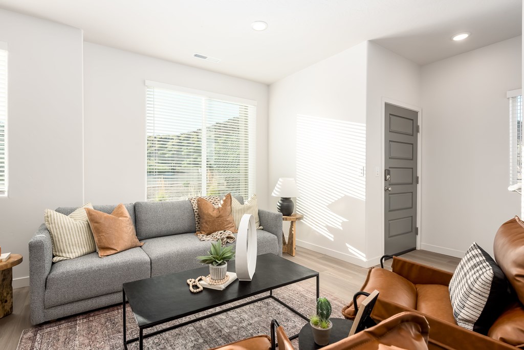 A living room with a grey sofa, a black coffee table, and a brown leather chair.