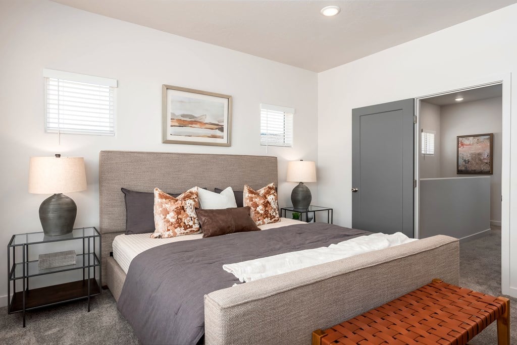 A bedroom with a large bed and a bench.