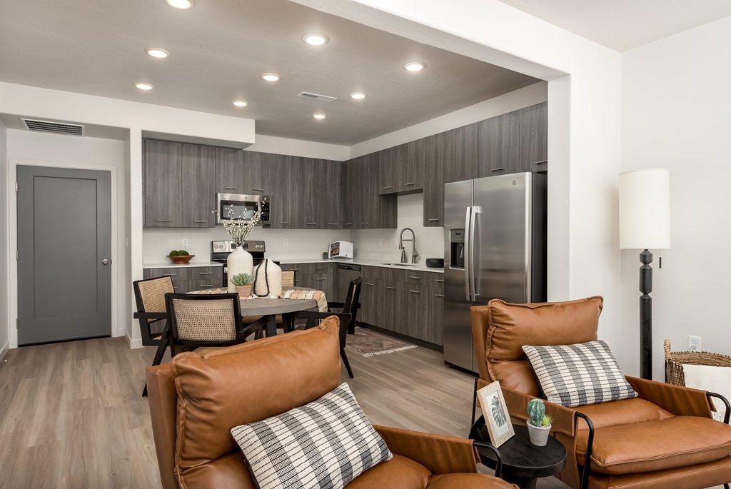 A modern kitchen with brown leather couches and a wooden floor.