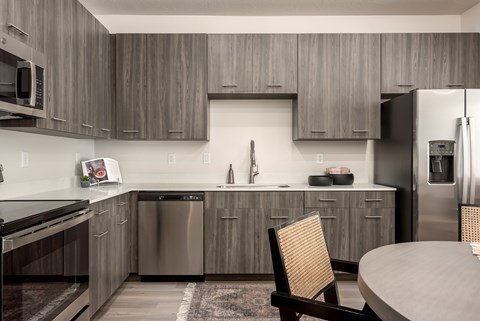A modern kitchen with a wooden chair and stainless steel appliances.