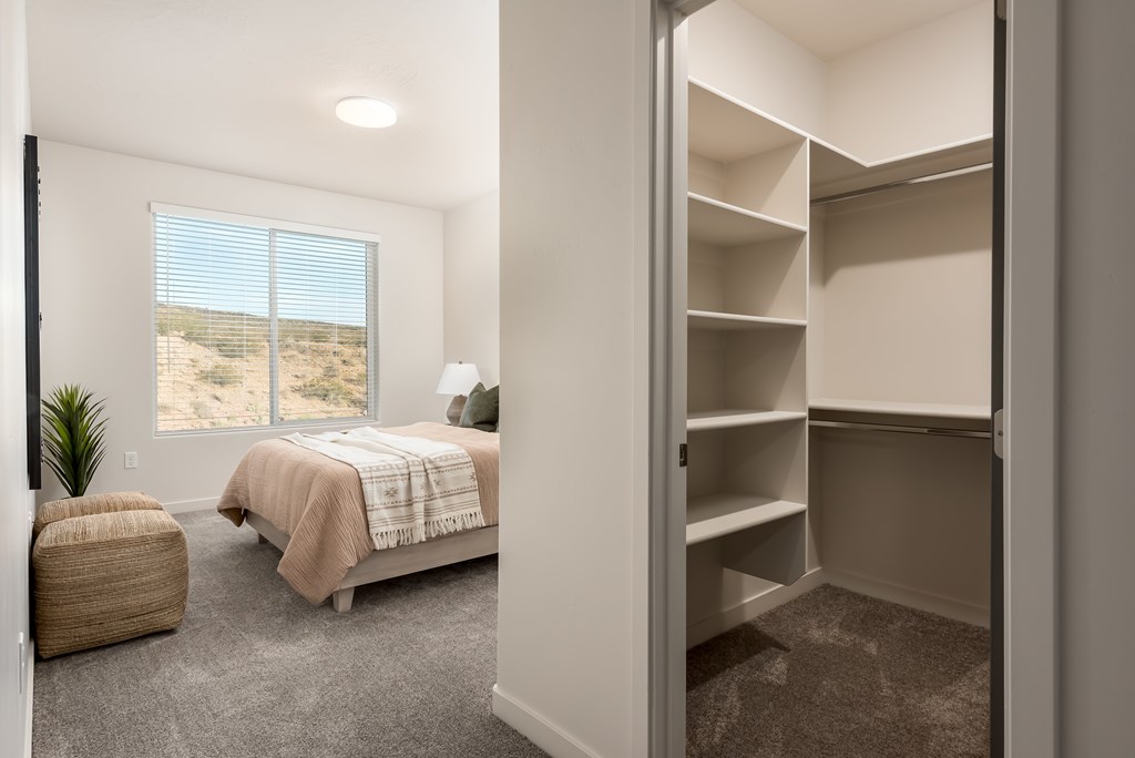 A bedroom with a bed, a chair, and a window overlooking the desert.