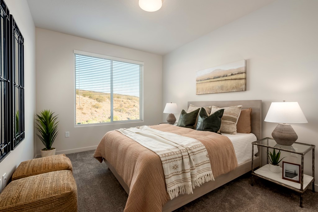 A bedroom with a large bed and a window overlooking a desert landscape.
