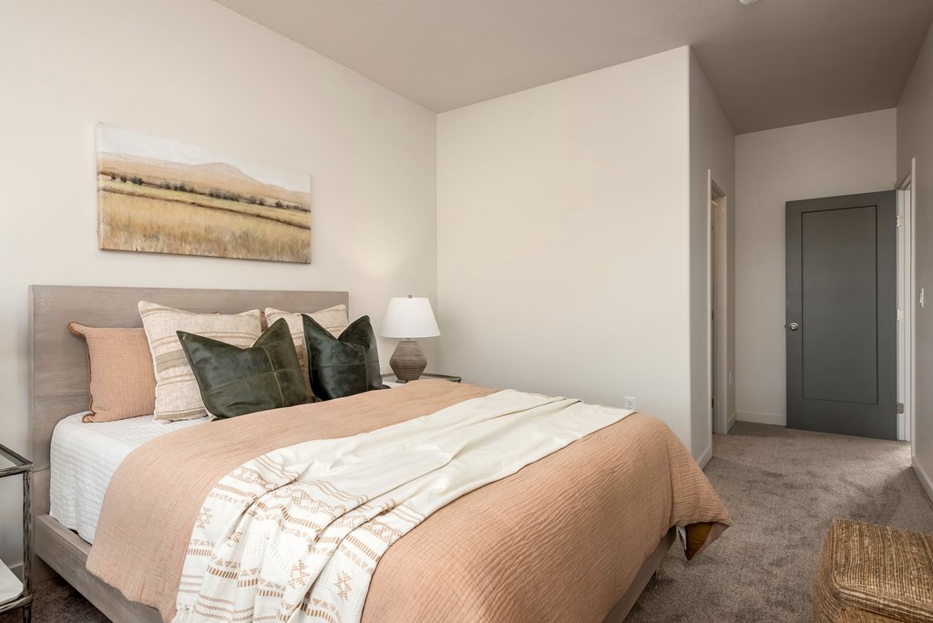 A bedroom with a bed, lamp, and painting on the wall.