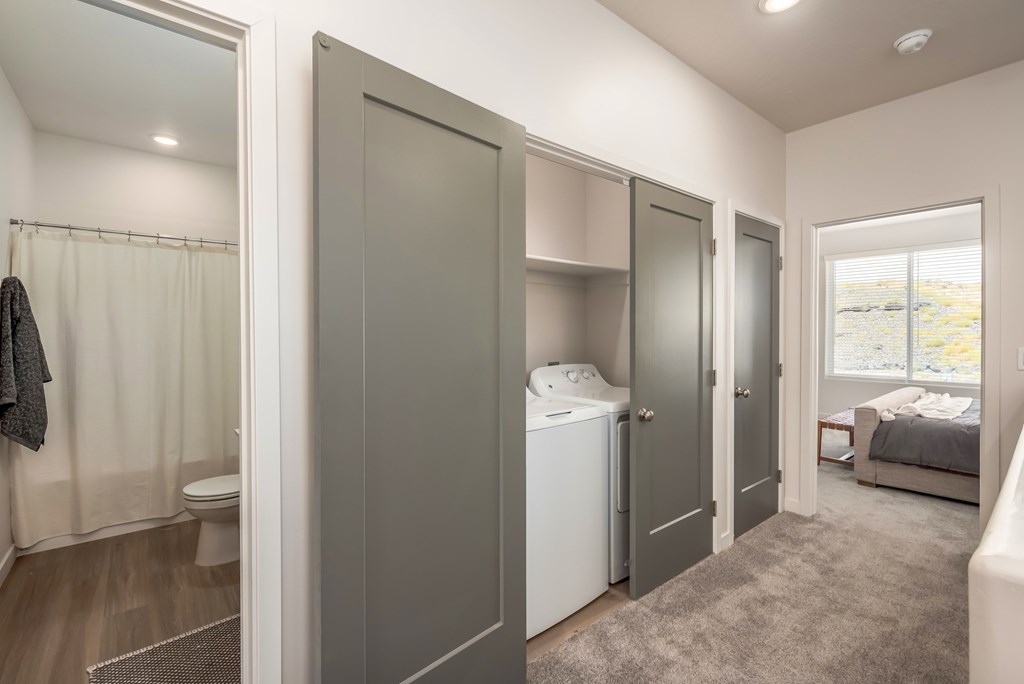 A small, modern bathroom with a washer and dryer built into the cabinetry.