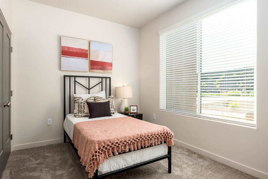 A bedroom with a bed, pillows, a lamp, and a painting on the wall.