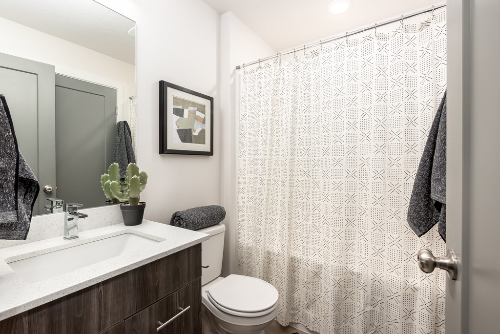 A bathroom with a toilet, sink, and shower curtain.