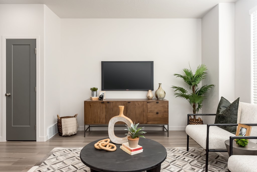 A living room with a flat screen TV mounted on the wall above a wooden cabinet.