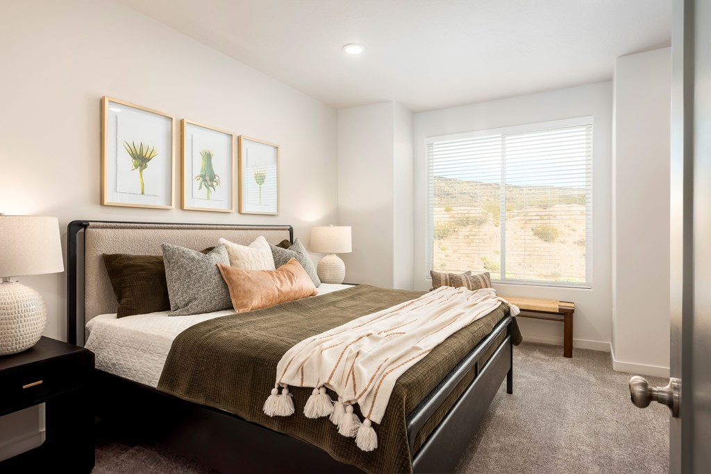 A bedroom with a large bed and a window overlooking a desert landscape.