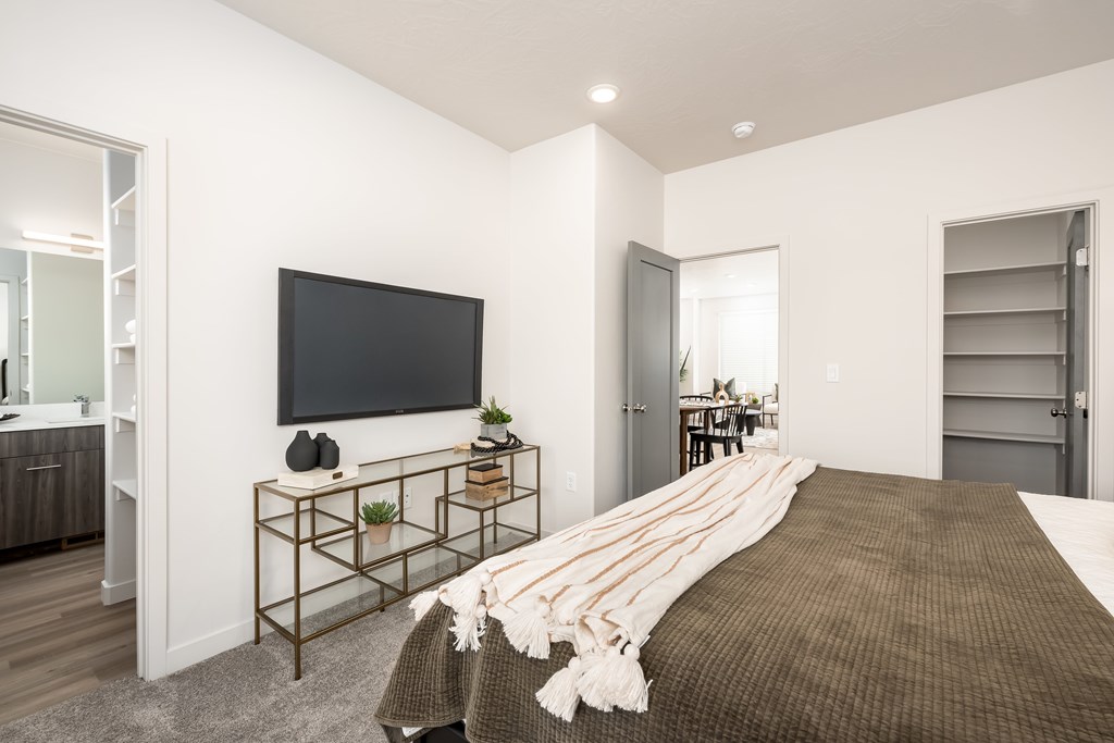 A bedroom with a large bed and a flat screen TV mounted on the wall.