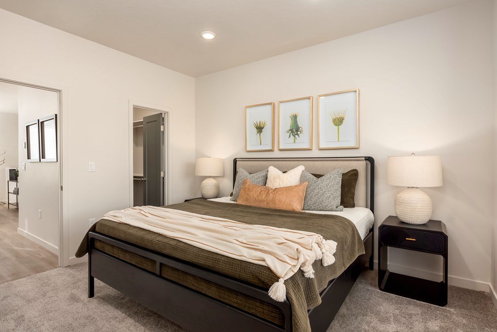 A bedroom with a bed, nightstands, and framed pictures on the wall.
