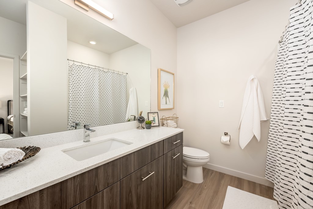A modern bathroom with a white sink and a white towel hanging on the shower curtain.