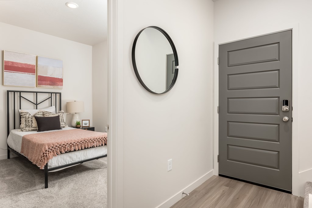 A bedroom with a bed, pillows, a round mirror, and a grey door.