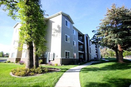 a walkway with trees and grass in front of an apartment building