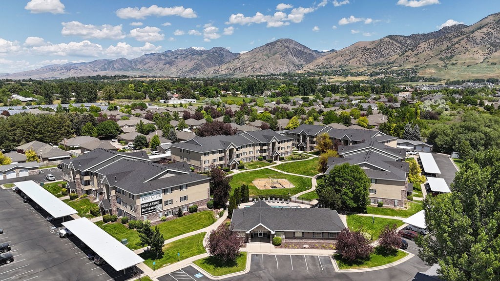 A large building complex with a parking lot in front and mountains in the background.