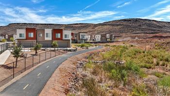 A road with a fence on the side and houses in the background.