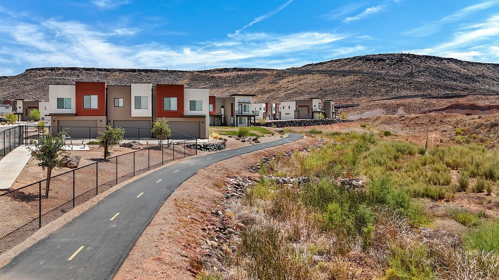 A road with a fence on the side and houses in the background.