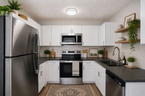 A kitchen with white cabinets and a black countertop.