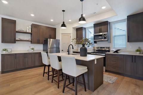 A modern kitchen with a center island and white chairs.