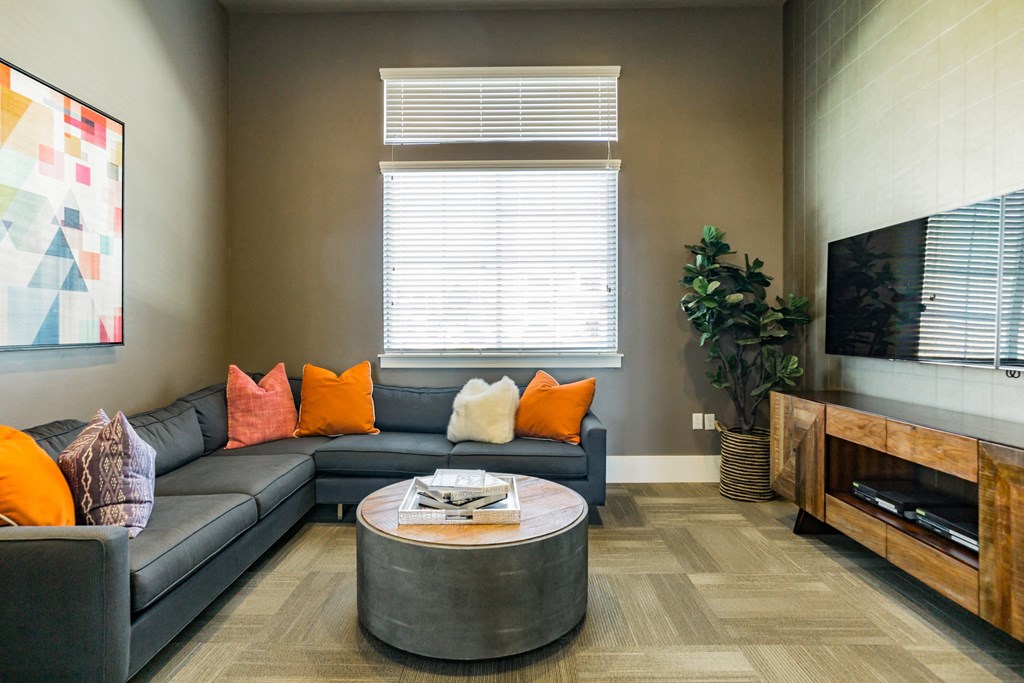 A bright living room area with a sectional couch and tv at Outlook Apartments for rent in Springville and Provo, UT.