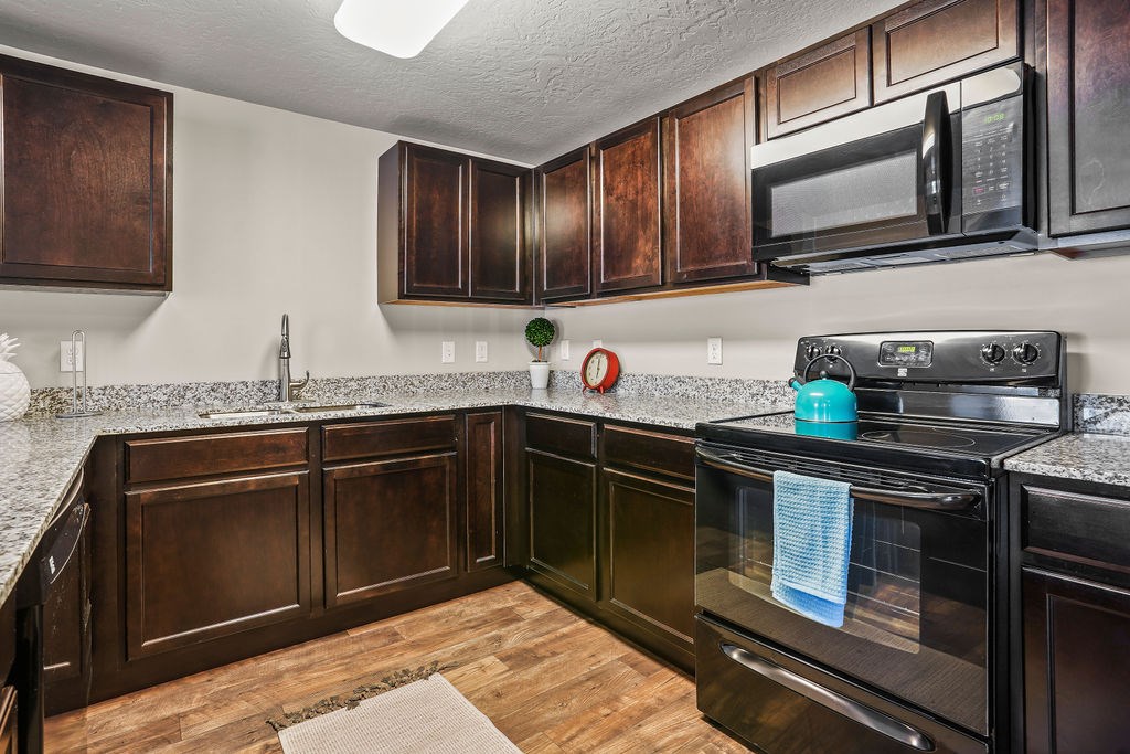 A kitchen with dark wood cabinets and black appliances.