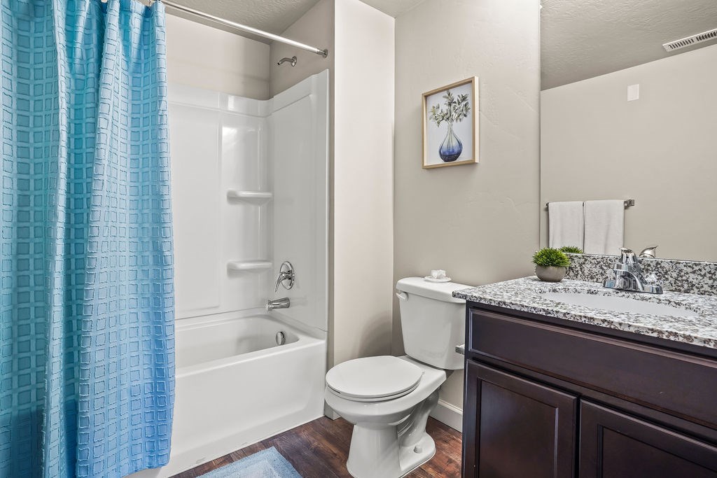 A bathroom with a white toilet, a white sink, and a blue shower curtain.