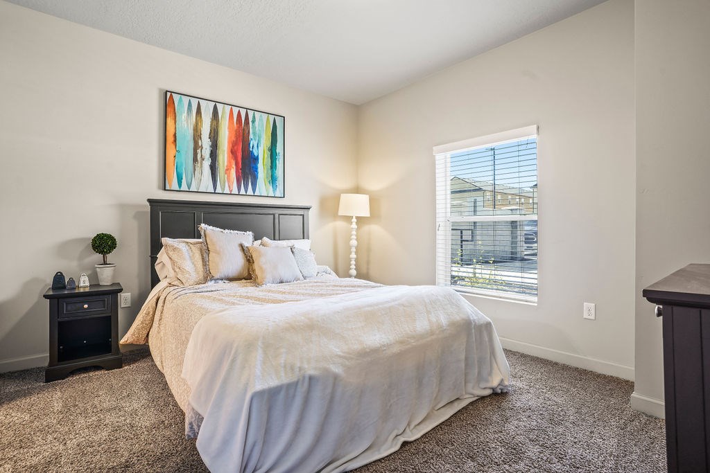 A bedroom with a large bed and a painting above it.