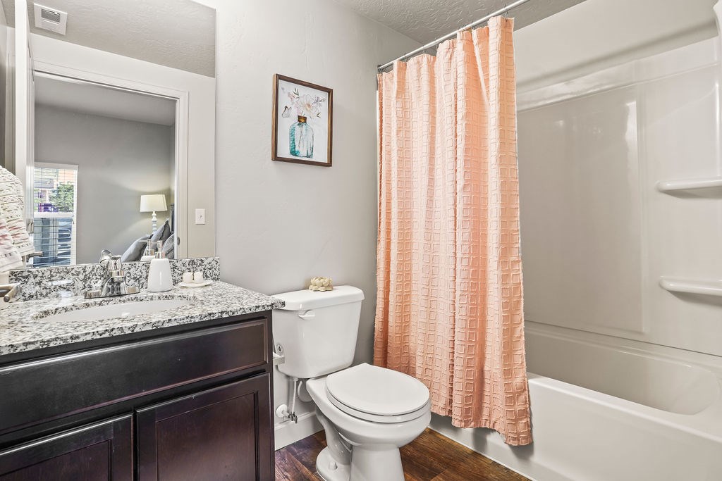 A white toilet sits next to a shower curtain in a bathroom.