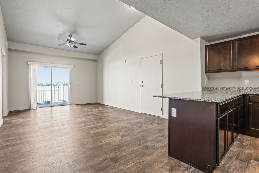 A spacious room with a ceiling fan and a kitchenette.