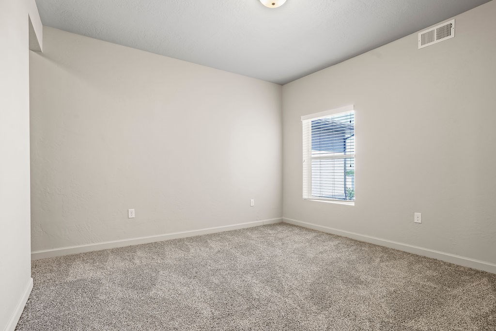 A room with a carpeted floor and a window with blinds.