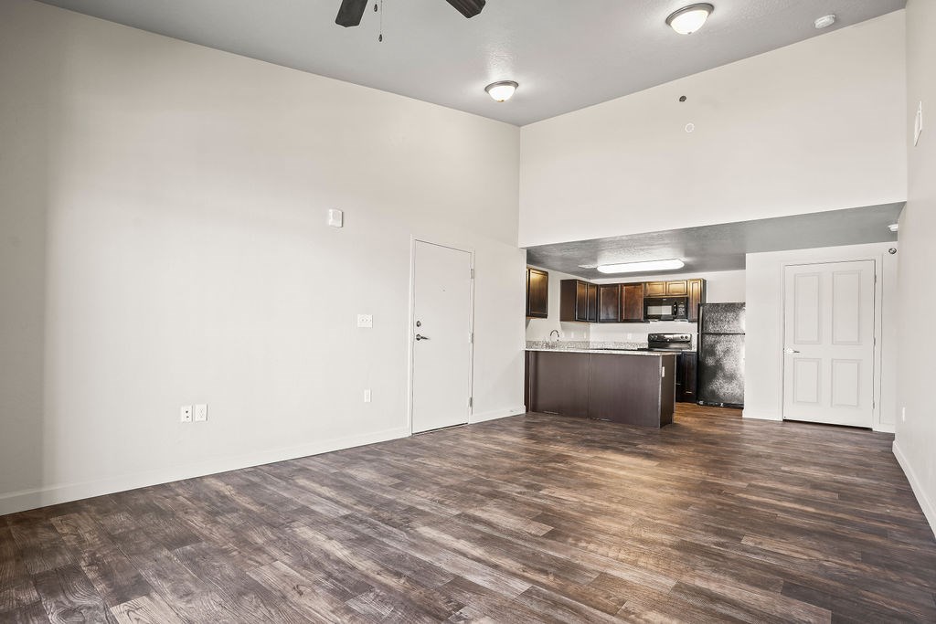 A room with a wooden floor and a kitchen area in the background.