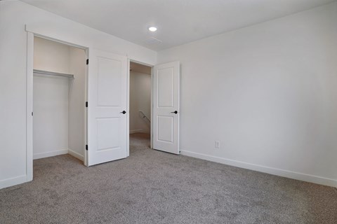 A room with carpeted floor and three white doors.