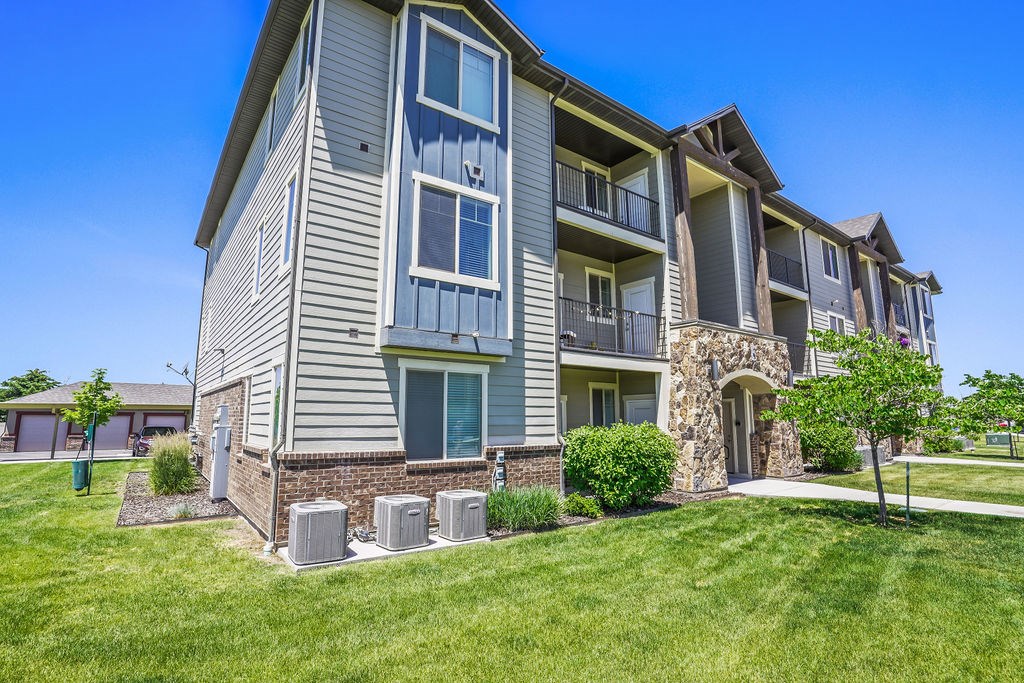 A large apartment building with a stone entrance and a green lawn in front.