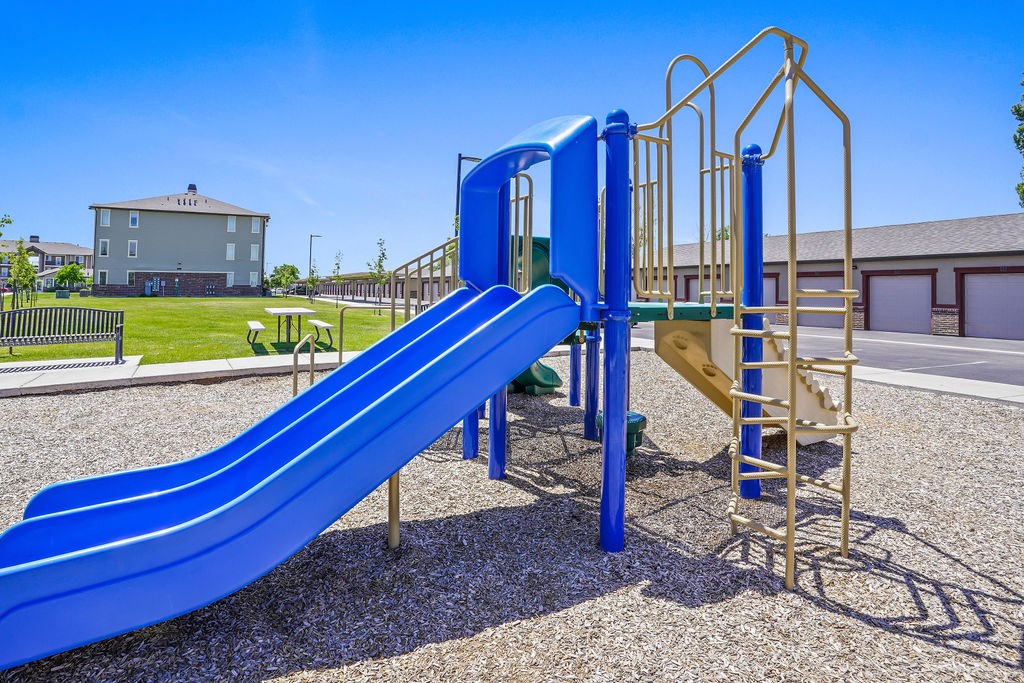 A blue slide in a playground with a yellow structure next to it.