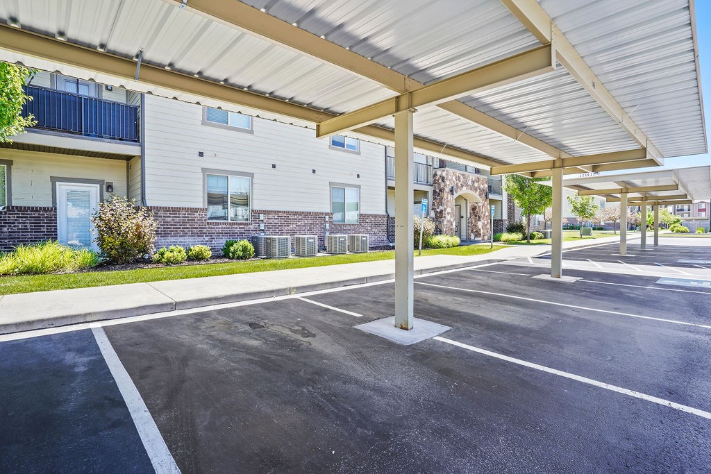 A parking lot with a white canopy and a building in the background.