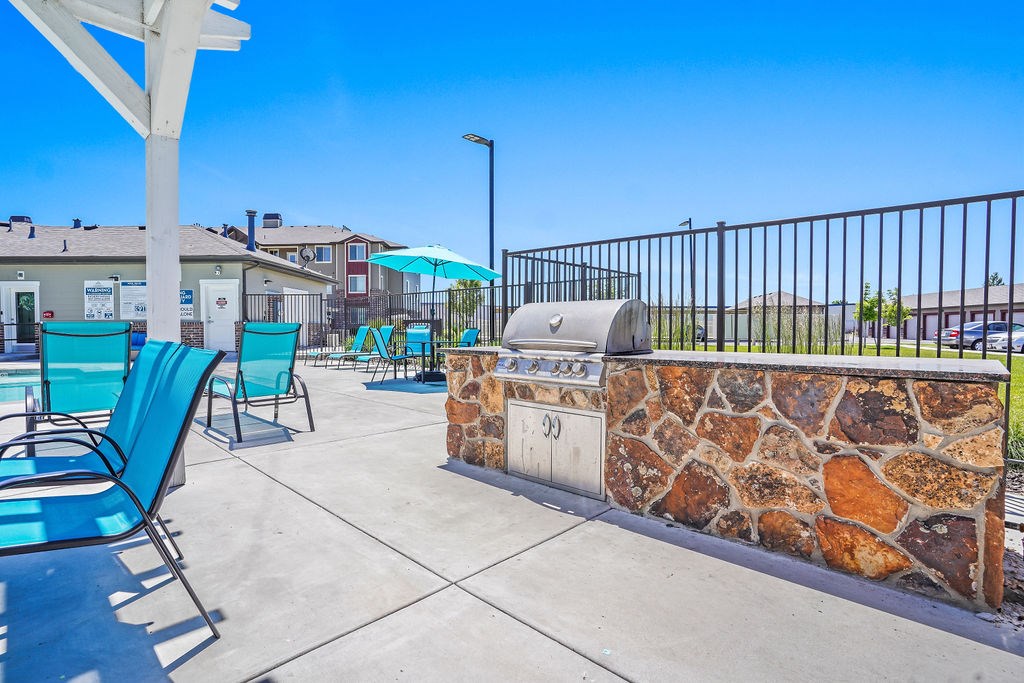 A sunny day at the outdoor seating area with blue chairs and a stone wall.