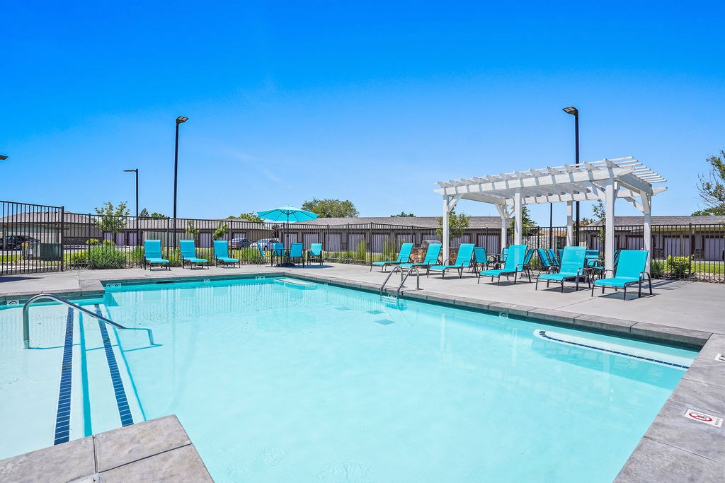 A pool with blue water and a white pergola.