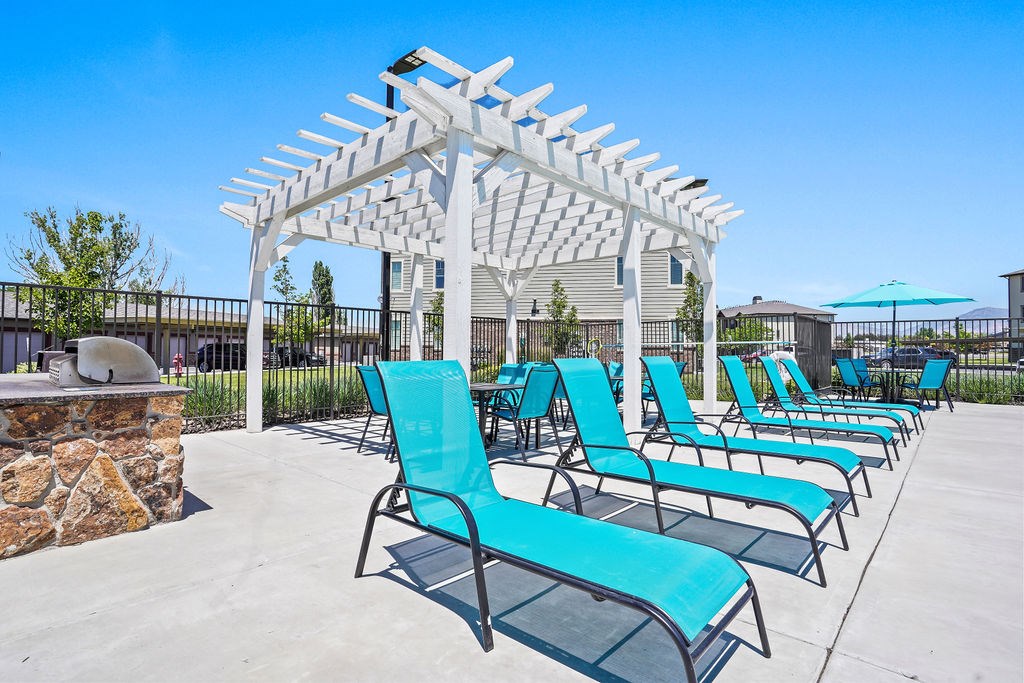 A row of blue chairs are lined up under a white pergola.