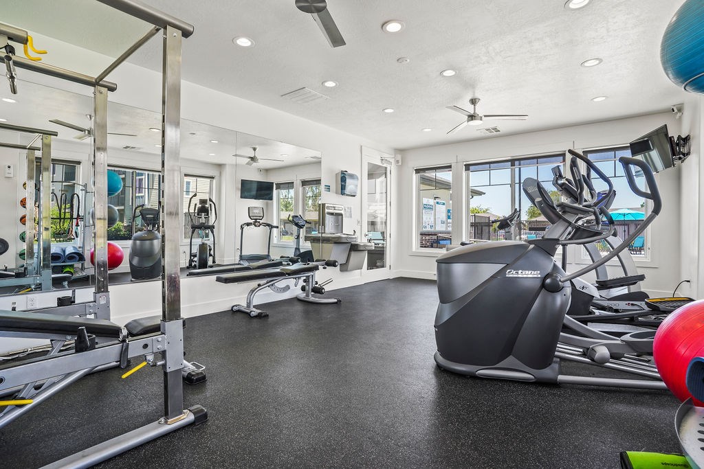 A spacious gym with a variety of equipment including a treadmill, weights, and a bench press.
